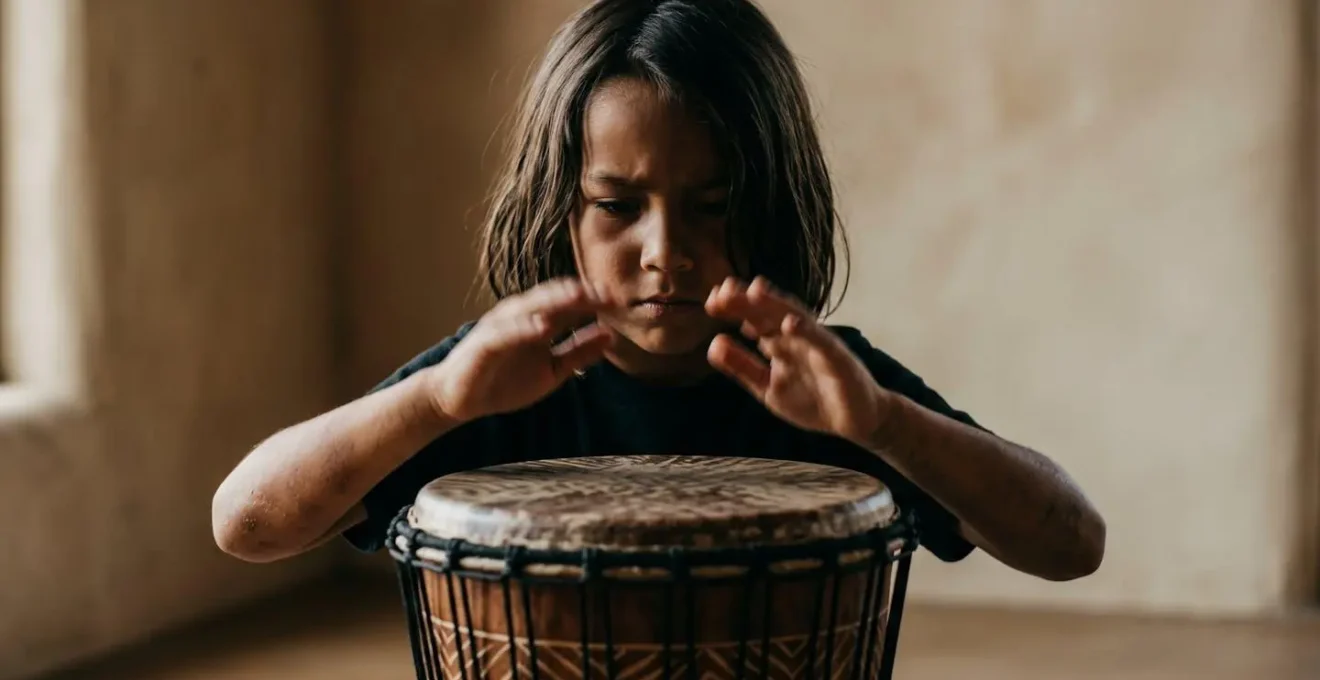 Young child deeply focused while playing hand drum, showing concentration and physical engagement with percussion instrument