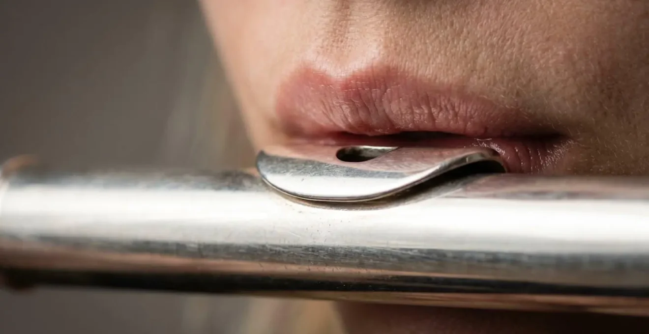 Extreme close-up of flute embouchure showing precise lip aperture and air direction