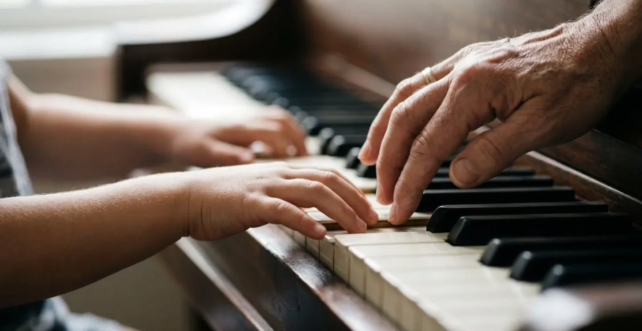 Close-up of hands gently guiding a child through first piano notes showing patience and encouragement