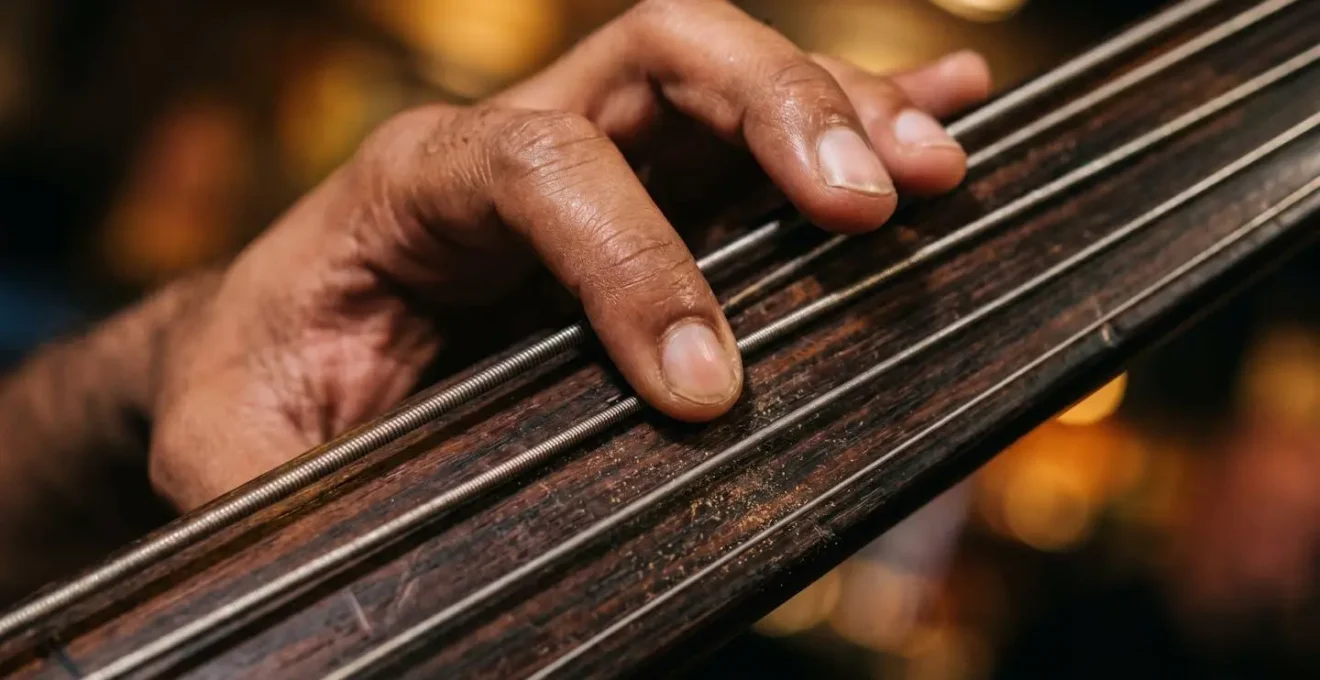 Close-up of a double bass player's hand walking across the fingerboard, capturing the rhythmic foundation of jazz improvisation